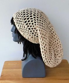 a mannequin head wearing a crocheted hat on top of a wooden table