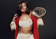 a woman holding a tennis racquet on top of her chest and wearing a sports bra