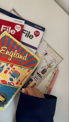 there is a person holding a book on the table with other books in front of them