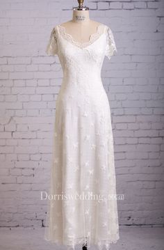 a white wedding dress on a mannequin stand in front of a brick wall