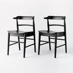 two black chairs sitting next to each other on a white surface with no one in it