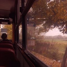 a view from the inside of a bus looking out at an open field and trees