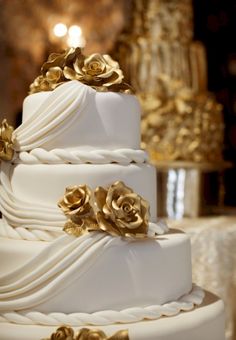 a white wedding cake with gold flowers on top