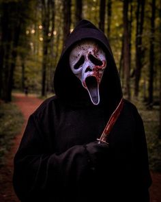 a person wearing a scary mask and holding a knife in the woods with their mouth open