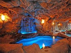 an indoor swimming pool surrounded by rocks and lights