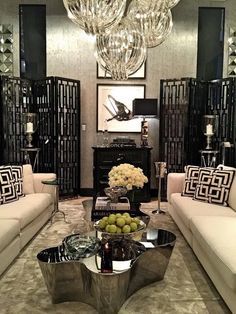 a living room filled with furniture and a chandelier hanging above the couches