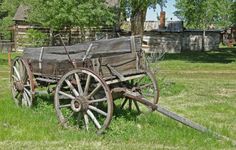 an old wagon with flowers in it sitting on the grass next to a white fence