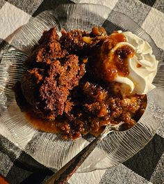 a glass plate topped with dessert and whipped cream on top of a checkered table cloth