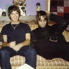 three young men sitting on a couch with one holding a beer