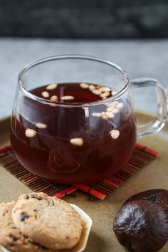 a glass mug filled with liquid next to cookies on a plate and another cookie beside it