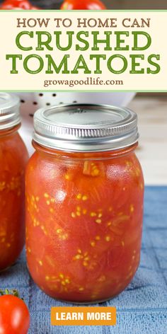 two jars filled with canned tomatoes on top of a blue towel next to a tomato