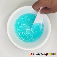 a person holding a spoon in a bowl filled with blue liquid