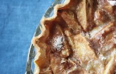 a pie with powdered sugar on top sitting in a glass dish, ready to be eaten