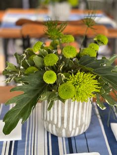 a vase filled with green flowers sitting on top of a blue and white table cloth