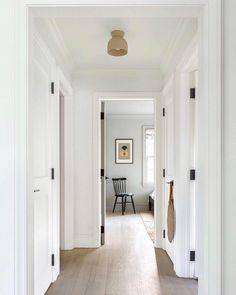 an empty hallway with white walls and wood flooring is seen from the entrance to the living room