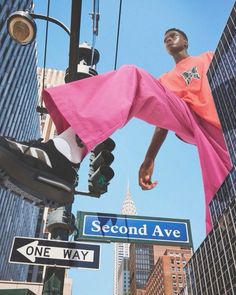 a man hanging from a traffic light in the air above a street sign that reads second ave