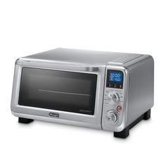 a silver toaster oven sitting on top of a white countertop next to a clock