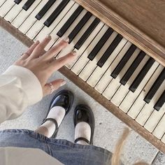 a person sitting at a piano with their hands on the keys and feet near them