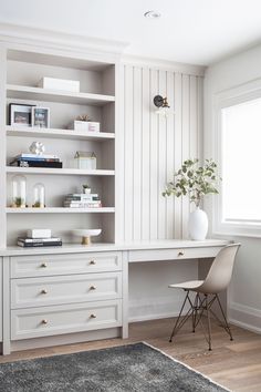 a white desk sitting in front of a window next to a chair and bookshelf