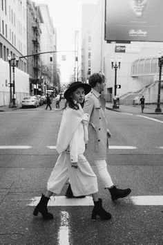 black and white photograph of two people crossing the street