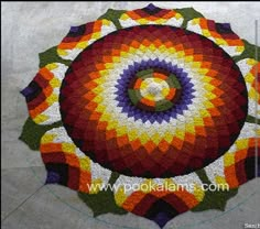 a circular crocheted rug with an orange, purple, yellow and green design