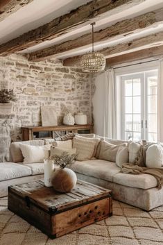 a living room filled with furniture and a fire place next to a stone wall covered in windows