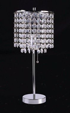 a crystal table lamp on a metal stand with a black background and white light behind it