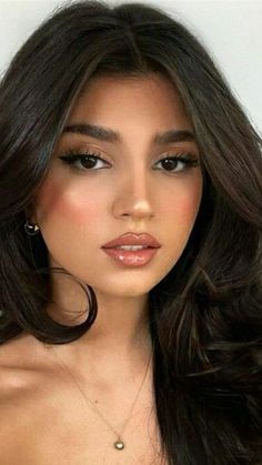 a woman with long dark hair and large hoop earrings on her neck is posing for the camera