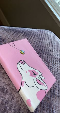 a pink canvas with a cow on it's face and a bee coming out of its mouth