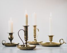 brass candlesticks with one candle lit and the other turned on