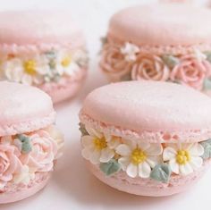 pink macaroons decorated with flowers on white surface