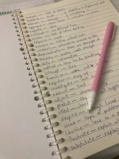 a notepad with writing on it and a pink pen resting on top of it