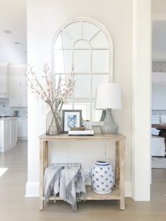 a table with vases and pictures on it next to a mirror in a living room