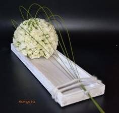 a bouquet of white flowers sitting on top of a piece of paper next to some grass