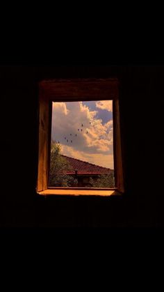 an open window with birds flying in the sky and clouds above it at night time