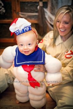 a woman is holding a baby dressed in an inflatable sumo wrestler costume and smiling at the camera