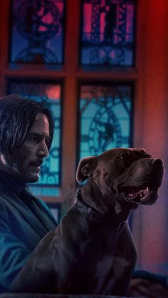 a man sitting next to a dog in front of stained glass windows