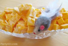 a mouse sitting on top of cheese in a glass bowl with it's tail sticking out