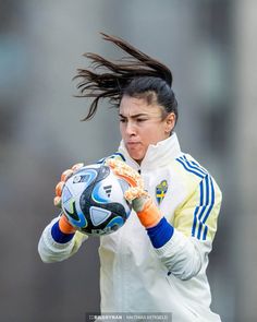 a woman holding a soccer ball in her hands