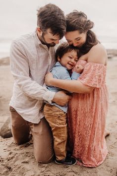 a man, woman and child hugging each other on the beach