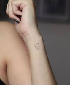 a woman with a small tooth tattoo on her arm