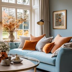 a living room filled with lots of furniture next to a large window covered in fall leaves