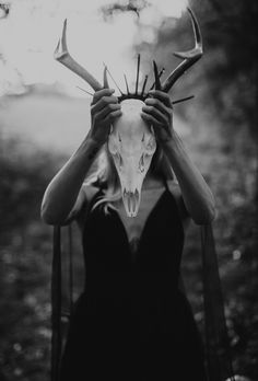 a woman holding up a deer skull in front of her face