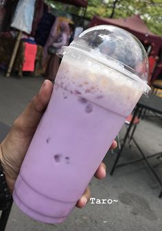 a person holding up a purple drink in their hand