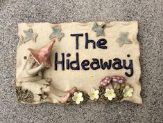 a sign that says the hideaway with gnomes and mushrooms