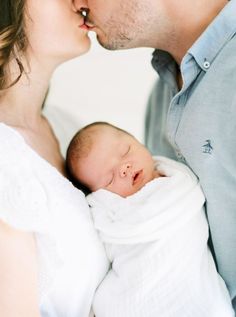 a man and woman kissing while holding a baby