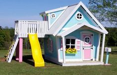 a little house with a slide and flower box in the grass next to it on a sunny day