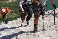 two men climbing up the side of a snow covered mountain