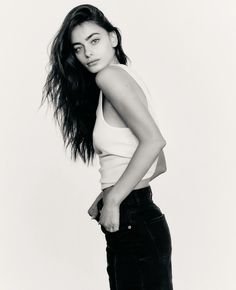 a black and white photo of a woman with long hair in tight jeans posing for the camera