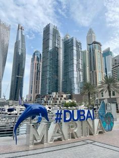 a sign that says dubai marina in front of some tall buildings with dolphins on it